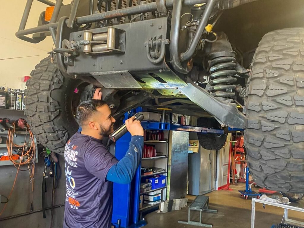 A mechanic reviews the bottom of a vehicle in service.